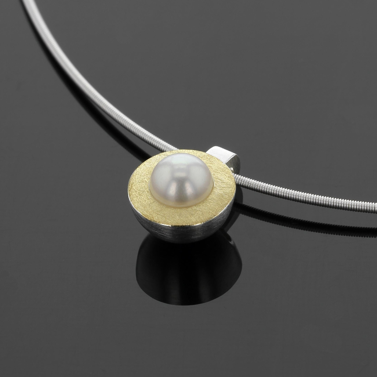 Round pendant in silver with a layer of yellow gold on its top surface with a freshwater pearl at its center