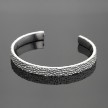 Oval shaped, open bangle in sterling silver with our unique lava rock texture.