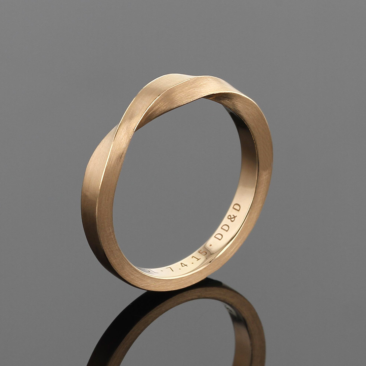Wedding band in rose gold with a twist at the top of the ring.