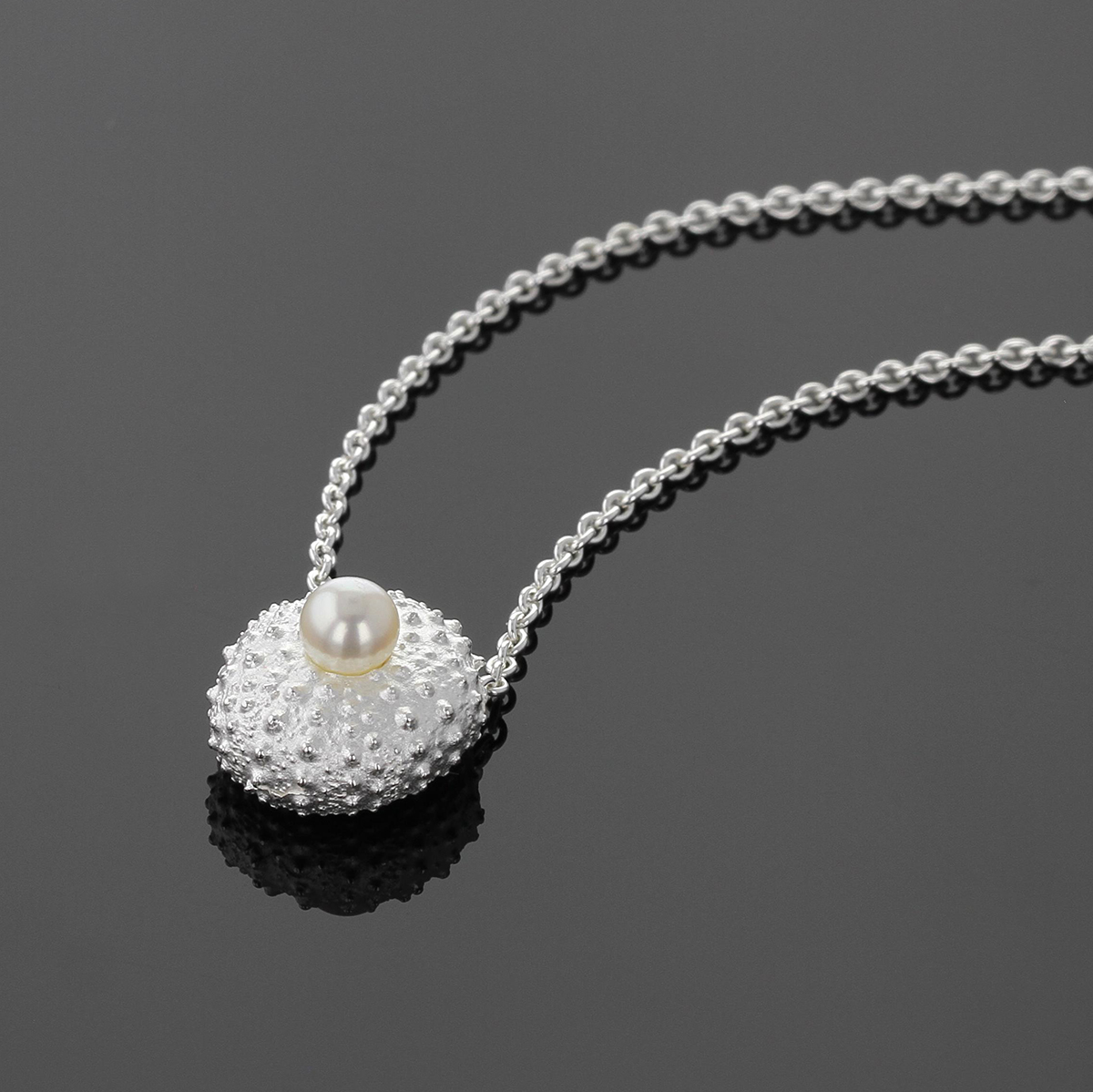 Mini sea urchin pendant in sterling silver with a freshwater pearl sitting at its center.