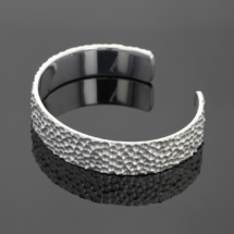 Wide bangle in silver with a hammered rock texture