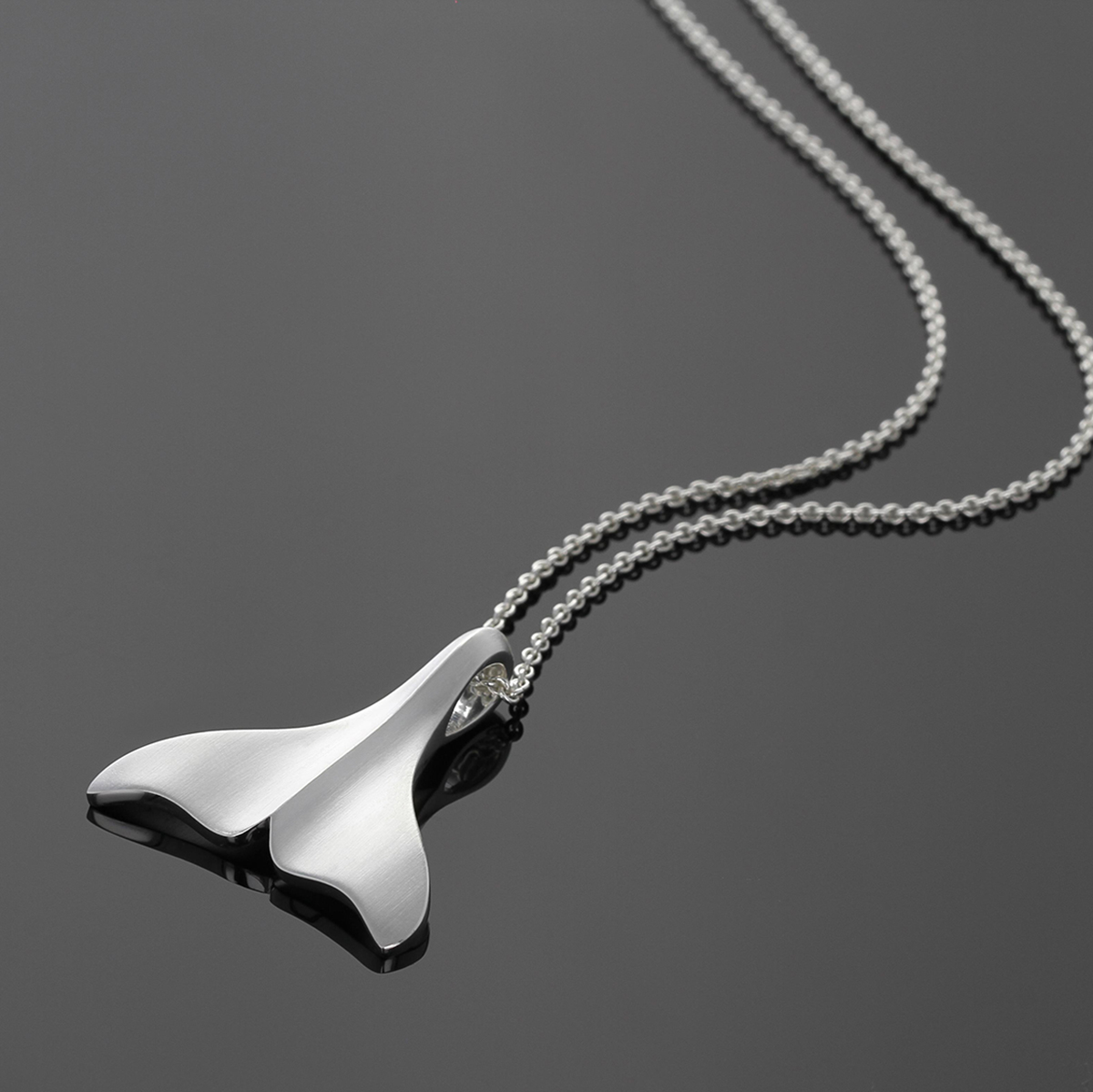 Whale fin pendant in sterling silver on a chain.