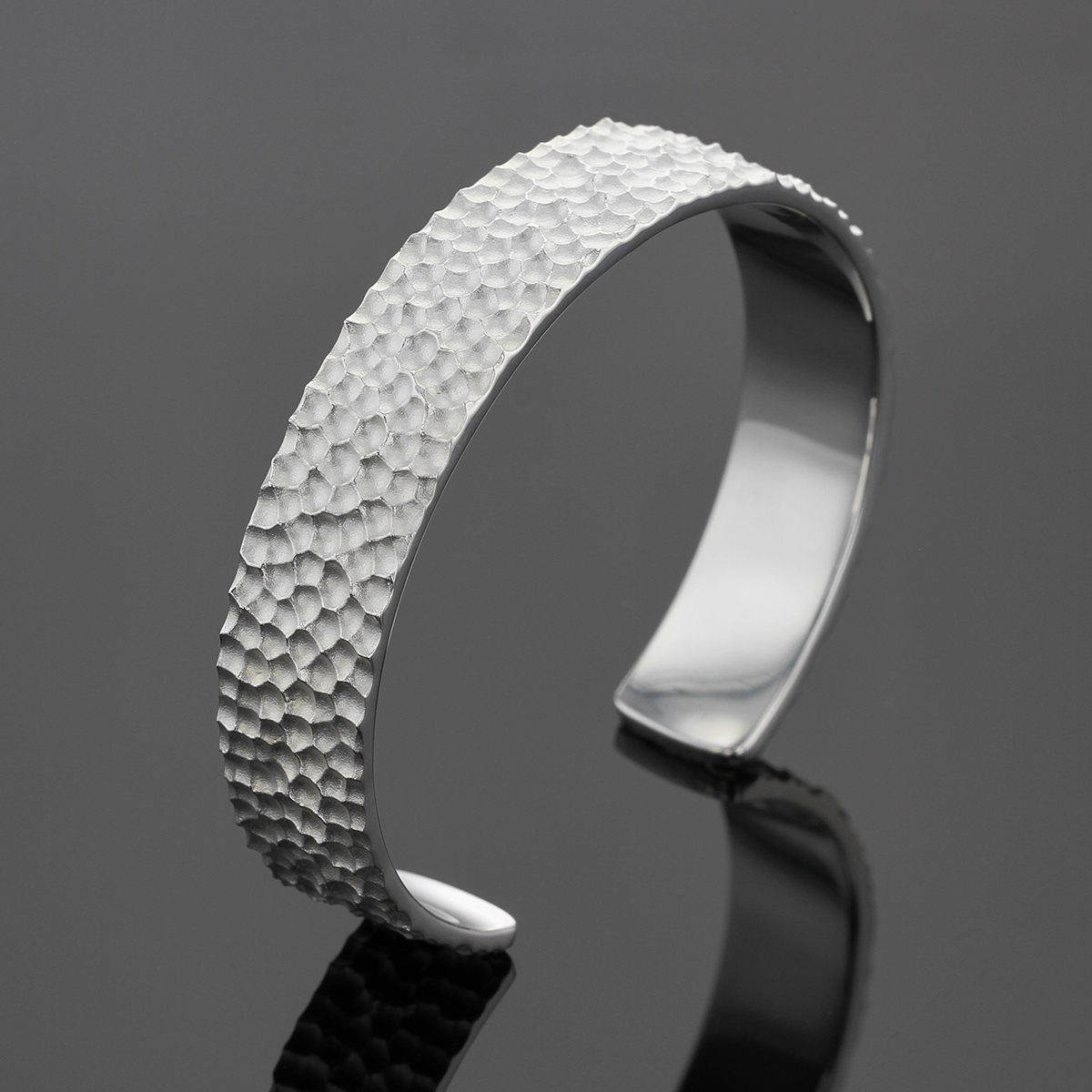 Wide bangle in silver with a hammered rock texture