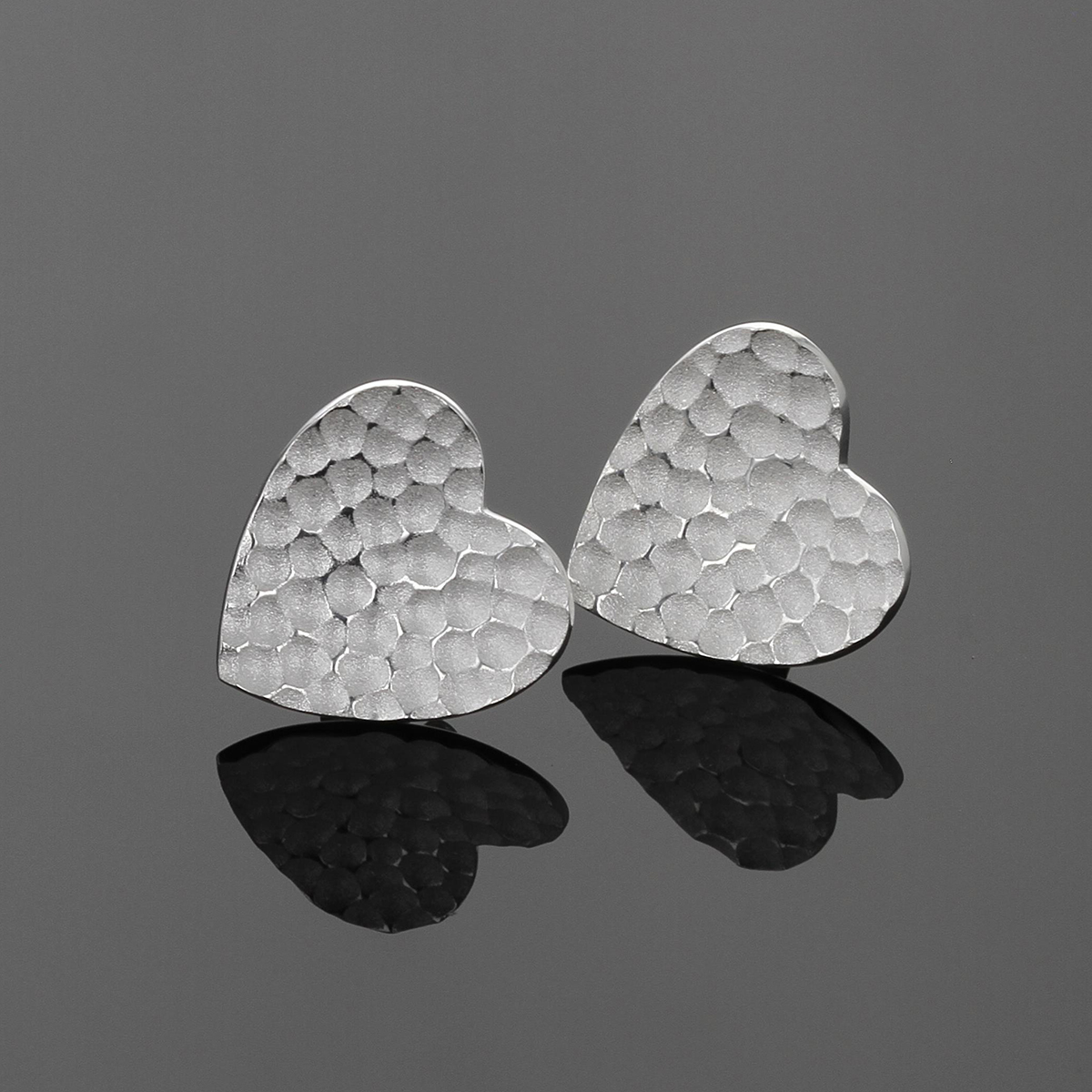 Silver heart shaped earrings with a lava texture