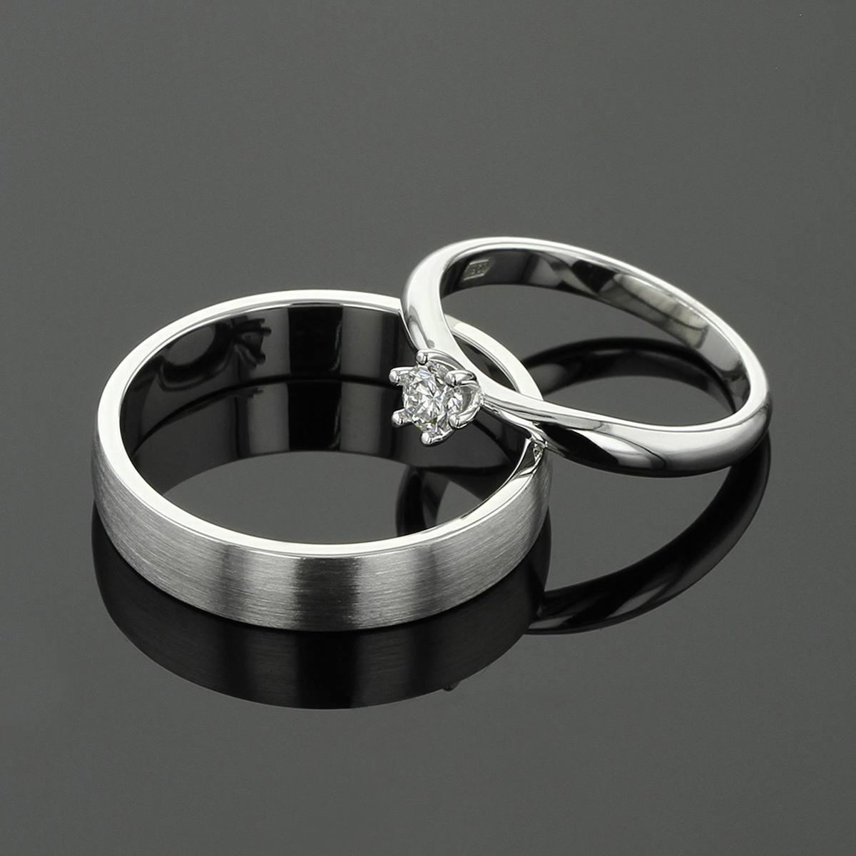 Simple, matted wedding band in white gold for him with a classic, solitaire diamond ring in polished white gold for her.