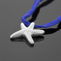 Seastar shaped pendant in matted silver on a dark blue silk ribbon