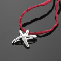 Seastar shaped pendant in polished silver on a pink silk ribbon