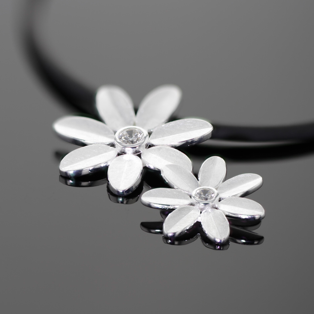 Flower pendant in brushed silver with a zirconia at its center