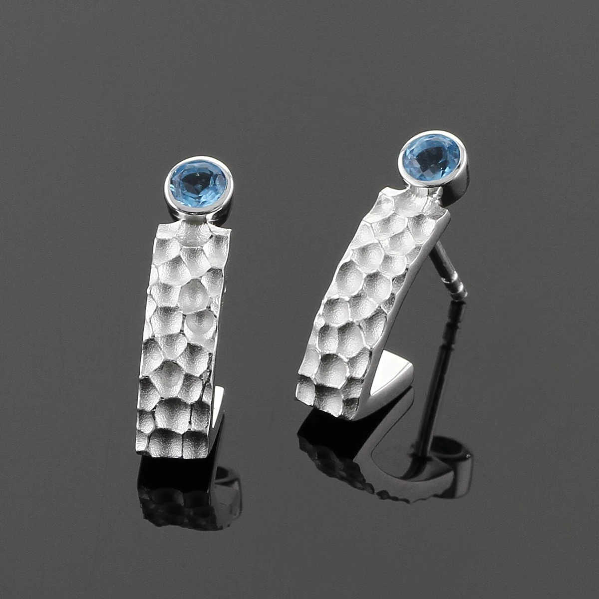 Earrings in silver with a lava rock texture and Blue Topas