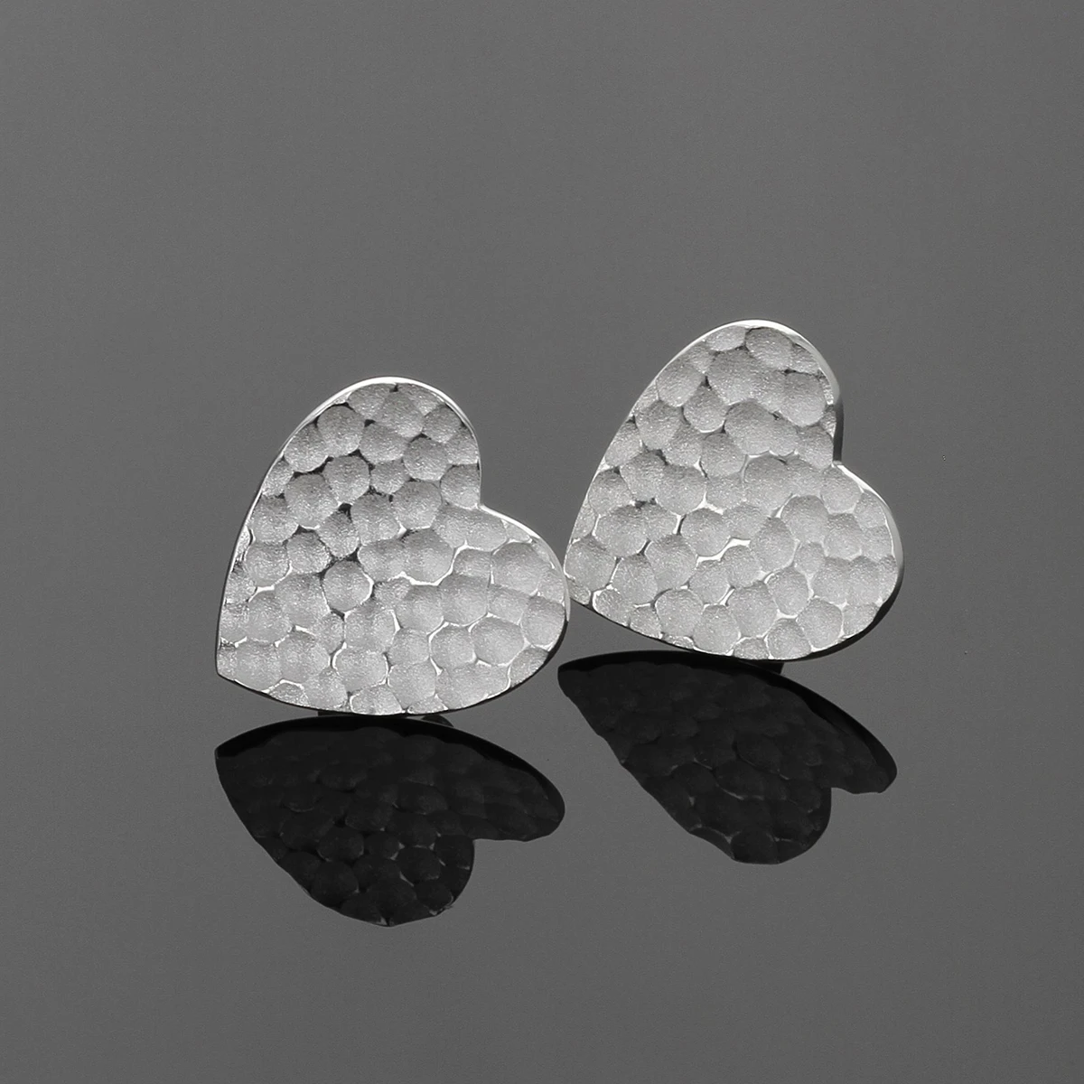 Silver heart shaped earrings with a lava texture